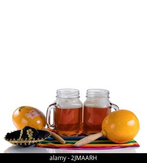 Bière avec objets de fête sur table en verre isolée sur fond blanc Banque D'Images