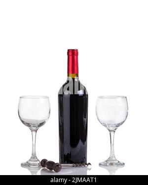 Bouteille de vin rouge non ouverte et verres isolés sur fond blanc Banque D'Images