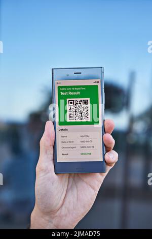 La main masculine tient le smartphone affichant un résultat de test négatif d'application de Covid-19. Test PCR Express, résultat numérique sur concept d'application mobile, gros plan Banque D'Images