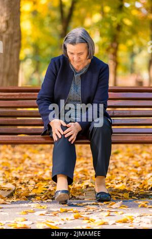 Senior woman having douleur au genou walking in park Banque D'Images