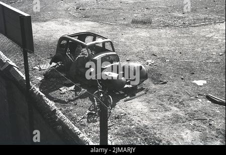 1960s, historique, vue de dessus de deux petits garçons assis à l'arrière d'une vieille épave d'une voiture, assis sur le terrain de déchets, Angleterre, Royaume-Uni. Banque D'Images