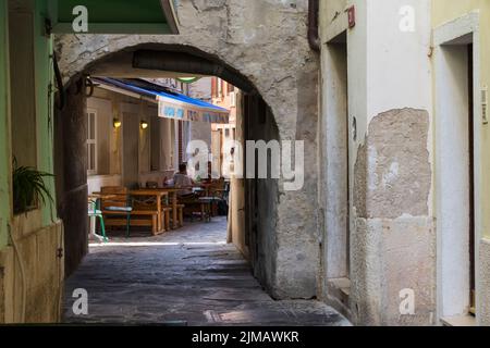 Vue à travers une porte voûtée sur une terrasse de restaurant dans une petite rue pittoresque dans le centre historique de Piran. Slovénie. Banque D'Images