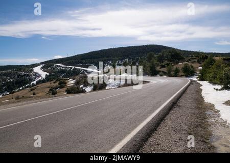 Courbes sur une route de montagne avec de la neige entre les arbres Banque D'Images