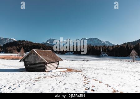 Une grange en bois sur le lac allemand de Gerold dans les alpes bavaroises et des traces dans la neige Banque D'Images