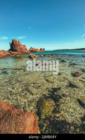 Une photo verticale d'une plage rocheuse contre une mer turquoise par une journée ensoleillée Banque D'Images