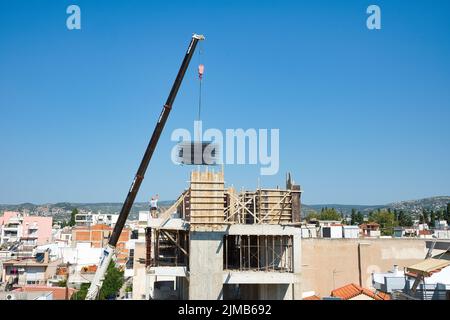 une grue automotrice extra-robuste décharge les matériaux en fer dans un bâtiment érigé Banque D'Images
