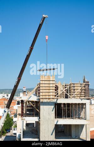 une grue automotrice extra-robuste décharge les matériaux en fer dans un bâtiment érigé Banque D'Images