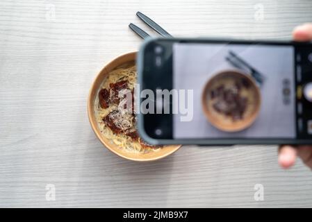 Shoot First Eat later concept, la prise de vue de dessus de pâtes à la sauce blanche aux truffes. Médias sociaux, partage de repas. Banque D'Images