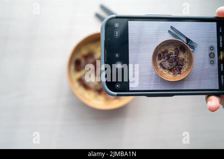 Shoot First Eat later concept, la prise de vue de dessus de pâtes à la sauce blanche aux truffes. Médias sociaux, partage de repas. Banque D'Images