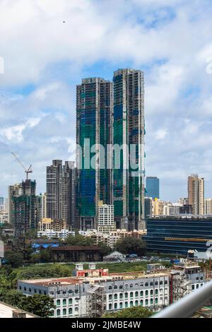 Bâtiment haut en construction. Côté avec grues, bâtiments de la ville et appartements avec ciel bleu et parc Banque D'Images