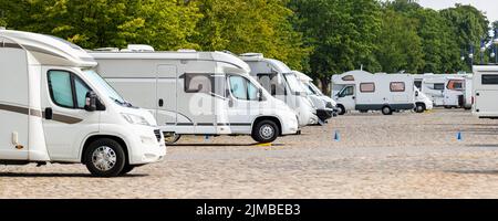 De nombreux véhicules de camping-car blancs modernes sont garés en rangée sur le site du camping-car de la ville de Magdeburg contre le pont de l'Elbe. Autocaravane Banque D'Images