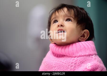 Une adorable petite fille indienne de 13 mois portant un poncho Banque D'Images