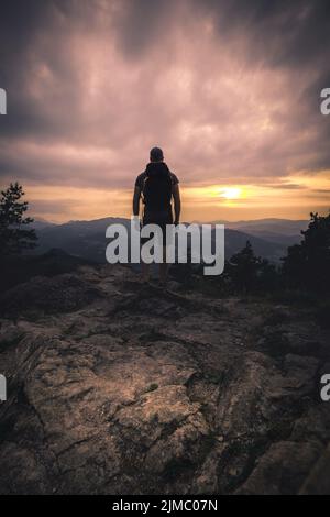 La silhouette de l'homme reste sur un pic de roche vif. Satisfaire les randonneurs profiter de la vue. Homme haut sur une falaise rocheuse regardant vers le bas vers le paysage Banque D'Images