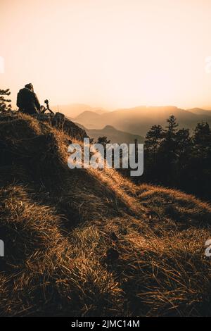 La silhouette de l'homme reste sur un pic de roche vif. Satisfaire les randonneurs profiter de la vue. Homme haut sur une falaise rocheuse regardant vers le bas vers le paysage Banque D'Images