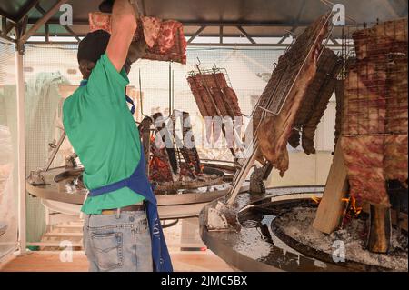 Cuisinier prépare la viande à rôtir sur le gril. Banque D'Images