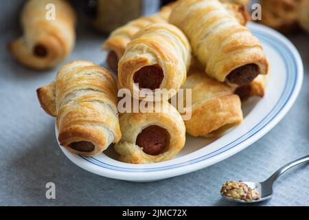 Cochons dans une couverture - petit rouleau de saucisse sur une assiette. Banque D'Images