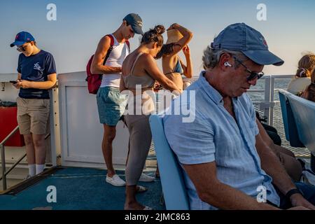 New York, New York, États-Unis. 4th août 2022. Les passagers du ferry de Fire Island (sur leurs cellules) retournent sur le continent après avoir passé du temps dans le village d'Ocean Beach Fire Island. Le populaire centre de villégiature d'été divertit les touristes de jour et les vacanciers saisonniers à l'atmosphère détendue de plage de soleil de sable et de surf. (Image de crédit : © Milo Hess/ZUMA Press Wire) Banque D'Images