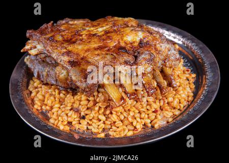 Côtelettes d'agneau sur le pilaf de bulgur. Côtes farcies isolées sur fond noir. Nom turc: 'Kaburga dolmasi'. Banque D'Images