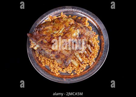 Côtelettes d'agneau sur le pilaf de bulgur. Côtes farcies isolées sur fond noir. Nom turc: 'Kaburga dolmasi'. Banque D'Images