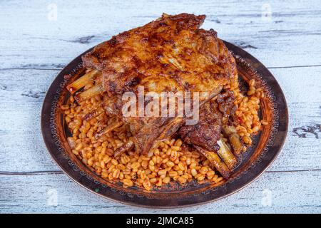 Côtelettes d'agneau sur le pilaf de bulgur. Côtes farcies isolées sur fond noir. Nom turc: 'Kaburga dolmasi'. Banque D'Images