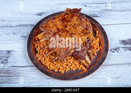 Côtelettes d'agneau sur le pilaf de bulgur. Côtes farcies isolées sur fond noir. Nom turc: 'Kaburga dolmasi'. Banque D'Images