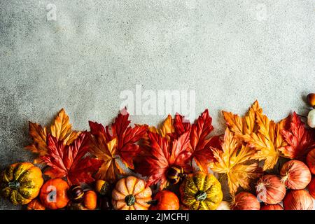 Cadre fait avec de fausses feuilles d'autumnl et de légumes de récolte sur le fond de béton Banque D'Images