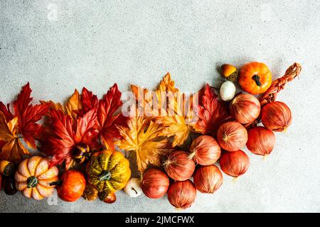 Cadre fait avec de fausses feuilles d'autumnl et de légumes de récolte sur le fond de béton Banque D'Images