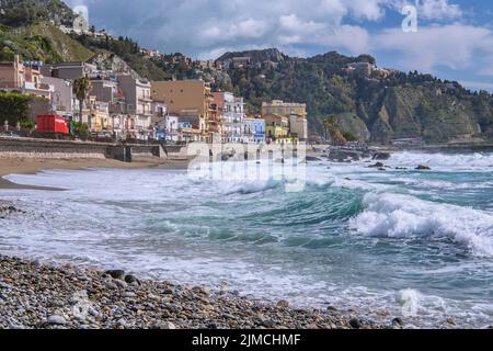 Surf en bord de mer en face de la promenade avec Taormina sur la colline, Giardini-Naxos, côte est, Sicile, Italie Banque D'Images