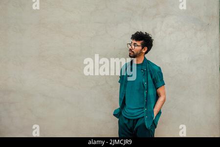 Beau pensif homme pendu sur un mur regardant vers le haut, inquiet homme avec les mains dans la poche regardant vers le haut, personne pensive regardant vers le haut avec l'espace de copie Banque D'Images