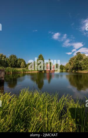 Deux pagodas rouges (Srila Prabhupada Puspa Samadhi) dans un lac, soleil dans la vallée de Krishna-voelgy Parolo Paroisse, Somogyvamos, Balaton Banque D'Images