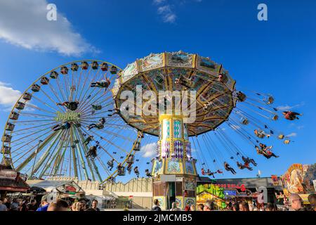 Crange, Herne, NRW, 05th août 2022. Les gens apprécient leur promenade dans un cadre traditionnel au joyeux joliment décoré sur fond de foire avec la roue Jupiter ferris. Le jour d'ouverture officiel du 2022 Cranger kirmes, 3rd le plus grand salon de la FONN d'Allemagne et le plus grand de ce genre, accueille des milliers de visiteurs qui apprécient les carrousels, les montagnes russes, les halls de bière, les stands de nourriture et d'autres attractions. Credit: Imagetraceur/Alamy Live News Banque D'Images