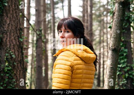 Femme en extérieur regardant l'appareil photo tout en voyageant dans les forêts de conifères en week-end Banque D'Images