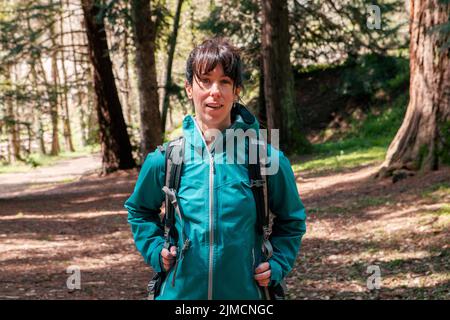 Femme en extérieur regardant l'appareil photo tout en voyageant dans les forêts de conifères en week-end Banque D'Images