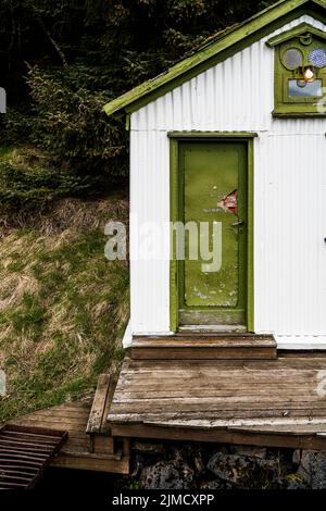 Extérieur de petite maison traditionnelle avec porte en bois vert et toit en campagne en Islande Banque D'Images