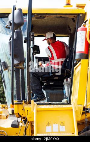 Vue latérale de l'opérateur de la moissonneuse-batteuse dans des récoltes de grains uniformes dans les champs agricoles lors de travaux en zone rurale Banque D'Images