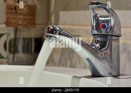 Chorro de agua cayendo de un grifo de un lavabo Banque D'Images