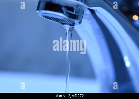 Pequeño chorro de agua cayendo de un grifo de un lavabo Banque D'Images