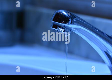 Pequeño chorro de agua cayendo de un grifo de un lavabo Banque D'Images