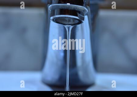 Pequeño chorro de agua cayendo de un grifo de un lavabo Banque D'Images