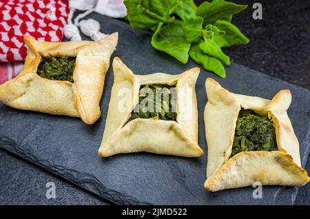 Délicieux plats libanais, sfiha aux épinards sur fond de pierre d'ardoise noire et turb libanais traditionnel Banque D'Images