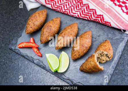 Délicieux plats libanais, kibbeh (kibe) avec sauces et citron sur pierre d'ardoise noire et fond de granit Banque D'Images