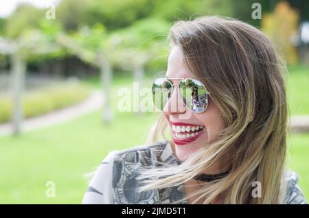 Jeune femme blonde heureuse qui rit sur la pelouse. Banque D'Images