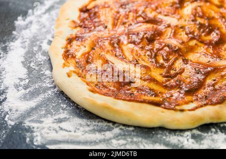 La préparation de pizza, close-up de la pâte à pizza avec la sauce tomate. Banque D'Images