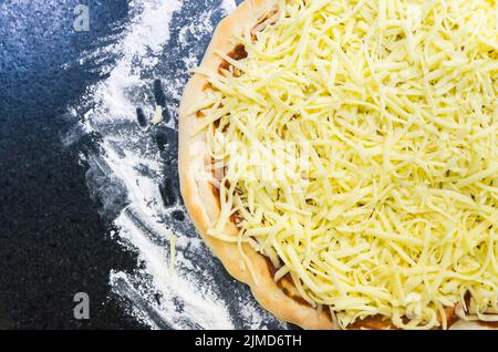 La préparation de pizza, close-up de la pâte à pizza avec la sauce tomate et mozzarella. Banque D'Images