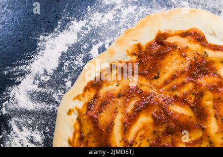 La préparation de pizza, close-up de la pâte à pizza avec la sauce tomate. Banque D'Images