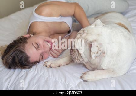 Belle femme au lit avec couchage chiot bouledogue anglais. Banque D'Images