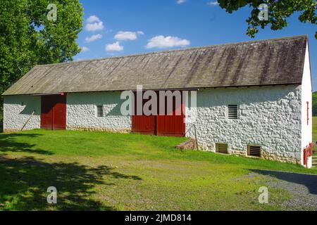 Ancienne grange coloniale américaine en pierre avec portes rouges Banque D'Images