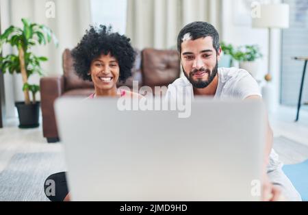 Connectez-vous et lancez-vous. Crier d'un jeune couple utilisant un ordinateur portable tout en faisant de l'activité à la maison. Banque D'Images