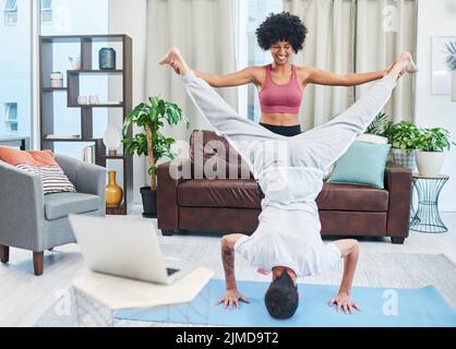 Couples le yoga est tellement amusant. Un jeune couple pratiquant le yoga dans leur salon. Banque D'Images
