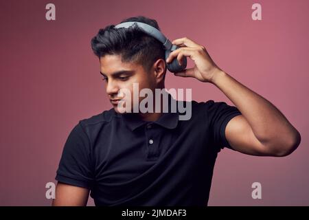 Une bonne musique est tout ce dont vous avez besoin. Photo en studio d'un jeune homme charmant portant un casque. Banque D'Images